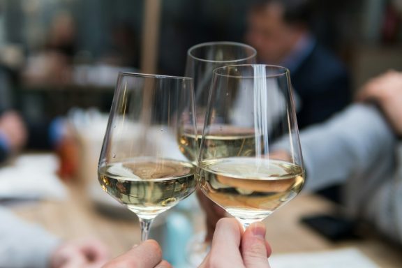 White Wine Celebration Toast Close-up of three people clinking glasses filled with chilled white wine in a toast.