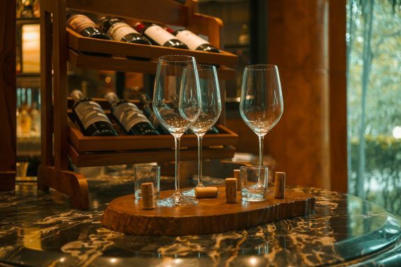 Elegant Wine Tasting Display Crystal wine glasses arranged on a marble table with vintage wine bottles in the background.