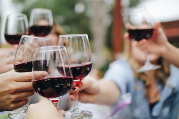 Outdoor Red Wine Toast Guests holding glasses of red wine for a cheer during an outdoor social gathering.
